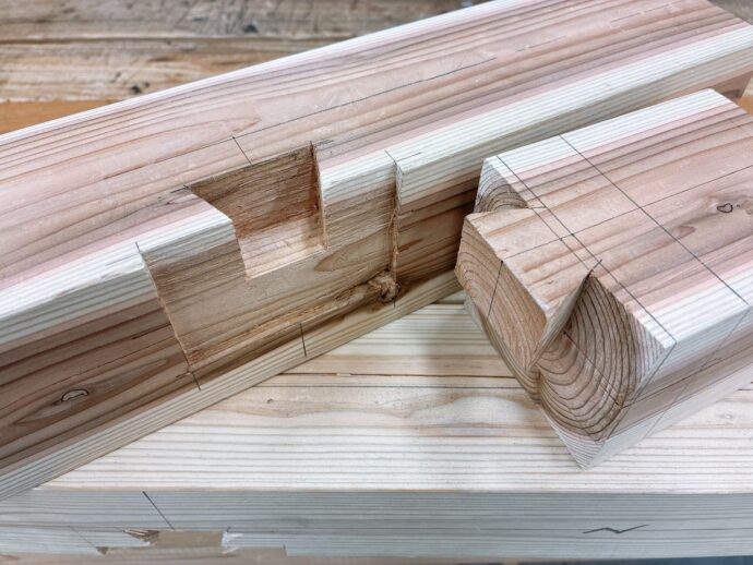 Stack of planed pine boards with pencil lines and notches for joinery.